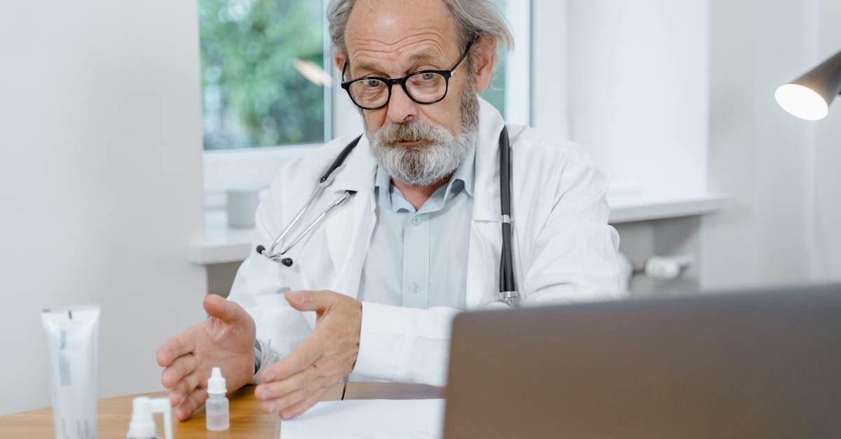 An elderly doctor in a white coat conducting an online medical consultation, focusing attentively.